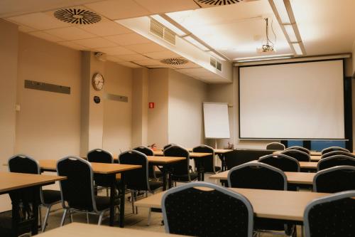 an empty classroom with tables and chairs and a whiteboard at Economy Silesian Hotel in Katowice