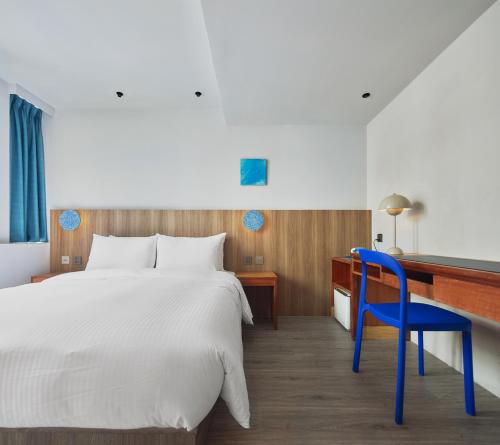 a bedroom with a bed and a desk and a blue chair at The Blue by Just Inn in Taipei