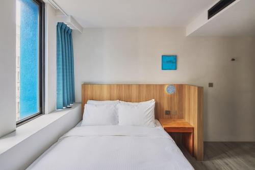 a bedroom with a bed with a wooden headboard and a window at The Blue by Just Inn in Taipei