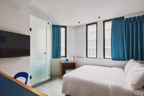 a bedroom with a bed and a flat screen tv at The Blue by Just Inn in Taipei