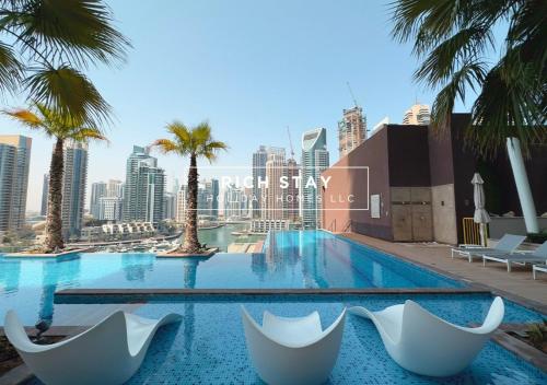 a swimming pool with chairs and palm trees in a city at Phenomenal 1BR in Marina Gate 2,Full Marina View in Dubai