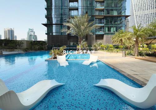 a swimming pool with white chairs and a large building at Phenomenal 1BR in Marina Gate 2,Full Marina View in Dubai