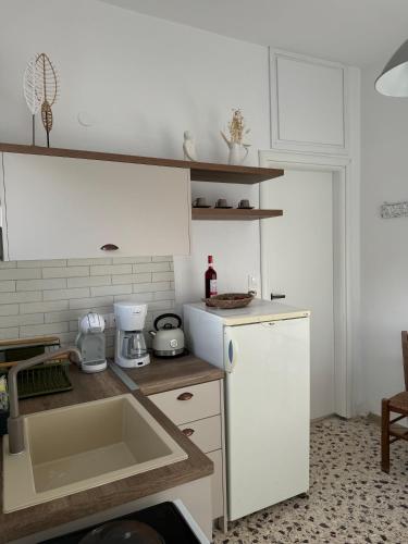 a kitchen with a sink and a white refrigerator at Akti Rooms And Studios in Livadion