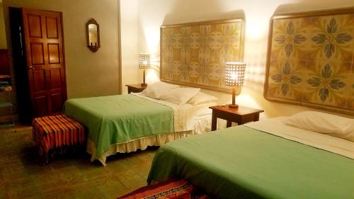 a hotel room with two beds with green sheets at Hotel La Polvora in Granada
