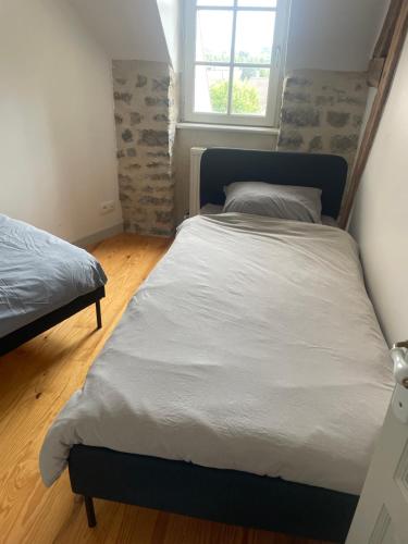 a bedroom with a large bed and a window at Le jardin du roitelet in Semur-en-Auxois