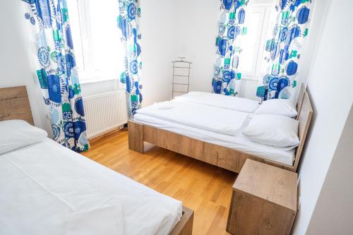 two beds in a room with blue and white curtains at Apartman A&S in Tomislavgrad