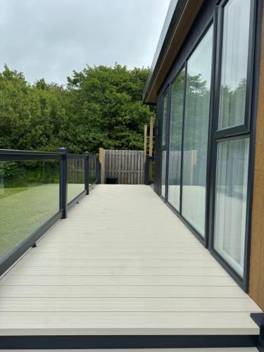a boardwalk leading to a building with windows at luxury hot tub glamping apartment in Ireleth