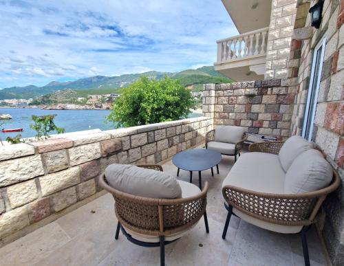 eine Terrasse mit Stühlen, Tischen und Ziegelwand in der Unterkunft Kazanegra Exclusive Apartments in Sveti Stefan