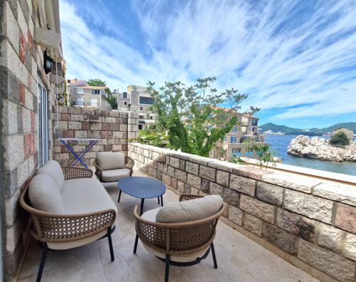 a balcony with chairs and a view of the water at Kazanegra Exclusive Apartments in Sveti Stefan