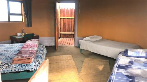 Bulungula Xhosa Community Lodge في Bulungulu: غرفة بسريرين وباب لغرفة بها نافذة