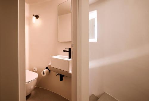 a bathroom with a white toilet and a sink at Windmill Karamitsos since 1859 in Tripití