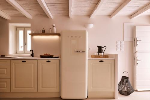 a white refrigerator in a kitchen with white cabinets at Windmill Karamitsos since 1859 in Tripití