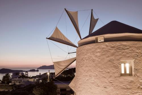 a building with a windmill next to a building at Windmill Karamitsos since 1859 in Tripití