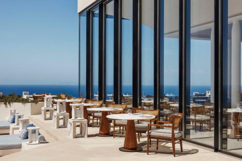 a restaurant with tables and chairs and the ocean at One&Only Kéa Island in Pisses