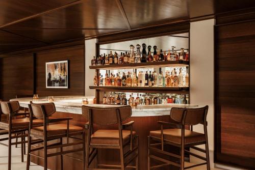 a bar with chairs and a counter with alcohol bottles at One&Only Kéa Island in Pisses