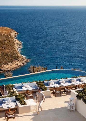a young boy walking past a pool at a resort at One&Only Kéa Island in Pisses