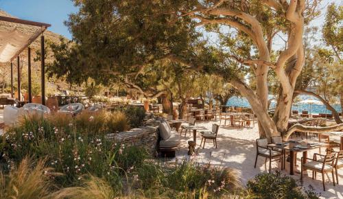a patio with tables and chairs under a tree at One&Only Kéa Island in Pisses