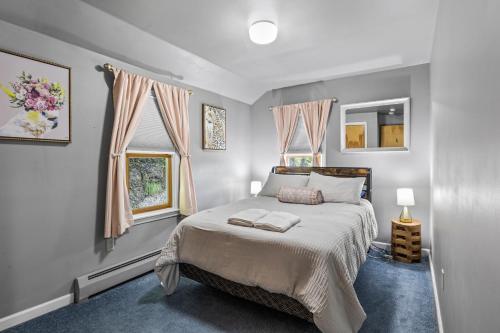 ein Schlafzimmer mit einem großen Bett und zwei Fenstern in der Unterkunft River Front Home In the Heart of Ithaca in Ithaca