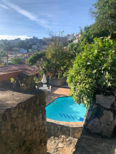 a swimming pool in a stone wall next to a yard at Casa na praia in Arraial do Cabo