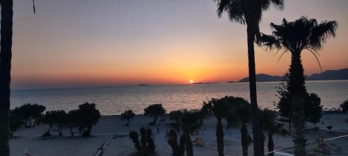 a sunset on a beach with palm trees and the ocean at Irene Studios in Mastichari