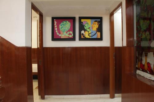 a hallway with two paintings on the wall and two doors at Happy Planet in Chennai