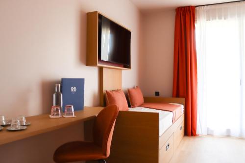a room with a bed and a desk and a tv at Hôtel Best of Both - Divonne-les-Bains in Divonne-les-Bains