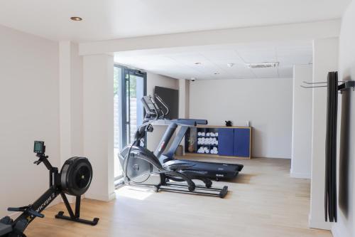 a room with a gym with a treadmill and exercise equipment at Hôtel Best of Both - Divonne-les-Bains in Divonne-les-Bains