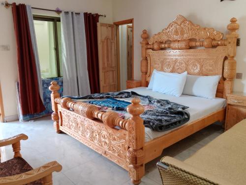 a bedroom with a large wooden bed with white pillows at Nambal Hotel, Kalam in Kalām