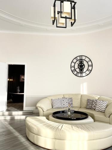 a living room with a couch and a clock on the wall at Trigon Palace in Budapest