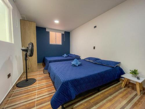 a bedroom with two beds with blue sheets and a fan at Coliving Casa encanto, Apartamento - Habitaciones, Laureles-América in Medellín