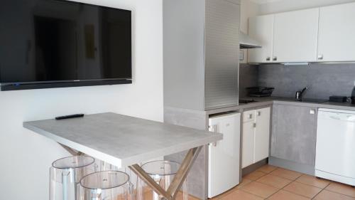 a kitchen with white cabinets and a table with stools at Le Cottage - Hotel & Spa in Argelès-sur-Mer