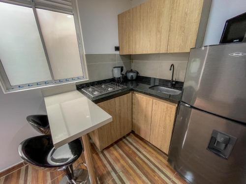 a kitchen with a stainless steel refrigerator and wooden cabinets at Coliving Casa encanto, Apartamento - Habitaciones, Laureles-América in Medellín
