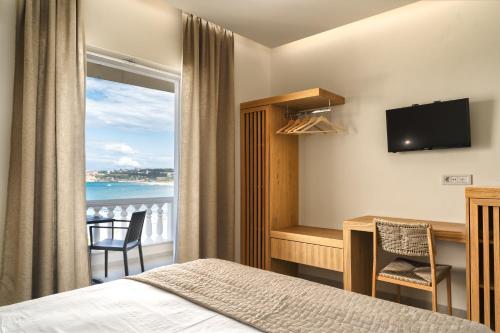 a hotel room with a bed and a desk and a window at Corali Beach in Tsilivi