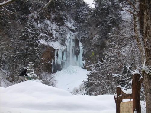 a person standing in front of a waterfall in the snow at Ryokan Tanaka in Takayama