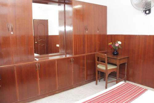 a bathroom with wooden cabinets and a table with a vase of flowers at Happy Planet in Chennai
