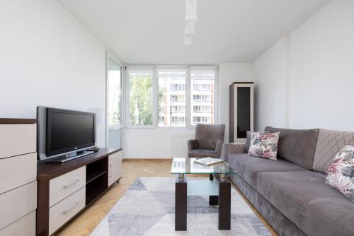 uma sala de estar com um sofá e uma televisão em Apartments Warsaw Królewska by Renters em Varsóvia