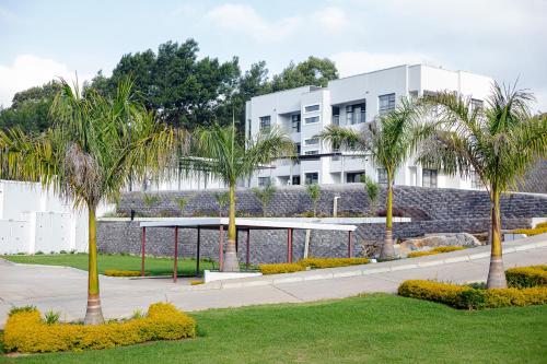 a building with palm trees in a park at Shobalenku Opulent apartments in Mbabane