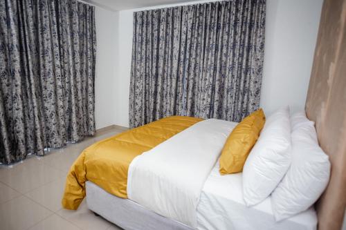 a bedroom with a bed with white sheets and yellow pillows at Shobalenku Opulent apartments in Mbabane