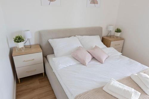 a bed with white sheets and pink pillows at Apartament Ponidzie in Zbludowice