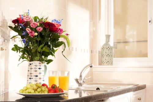 a table with a plate of fruit and a vase of flowers at Bayfort Sea Studio - Comfortable Couples Retreat with Stunning Coastal Views in Torquay