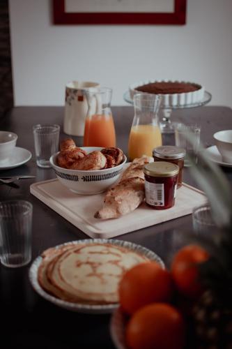 a table topped with plates of food and orange juice at La Demoiselle in Les Ponts-de-Cé