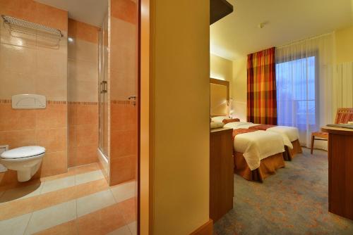 Maxmilian Lifestyle Resort في لوسين: غرفه فندقيه سريرين وحمام
