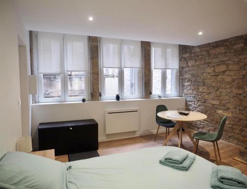 une chambre avec un lit, une table et des fenêtres dans l'établissement Appartement cosy en plein centre historique de Besançon, à Besançon