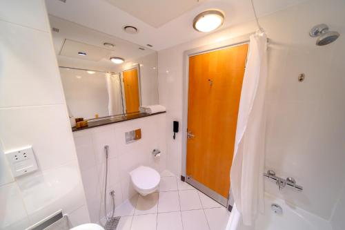 a bathroom with a toilet and a wooden door at Premier Inn Abu Dhabi Airport Business Park in Abu Dhabi