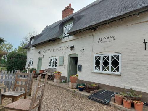 a white building with a bench in front of it at Straw Bale Cottage in Halesworth