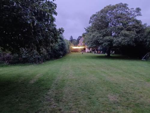 a field with trees and a building in the distance at Straw Bale Cottage in Halesworth