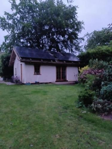 a small white house in a yard with green grass at Straw Bale Cottage in Halesworth