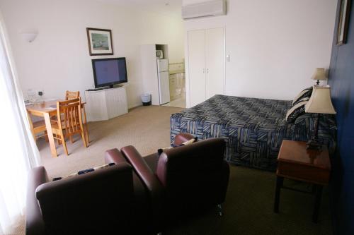 a bedroom with a bed and a couch and a television at Criterion Hotel-Motel Rockhampton in Rockhampton