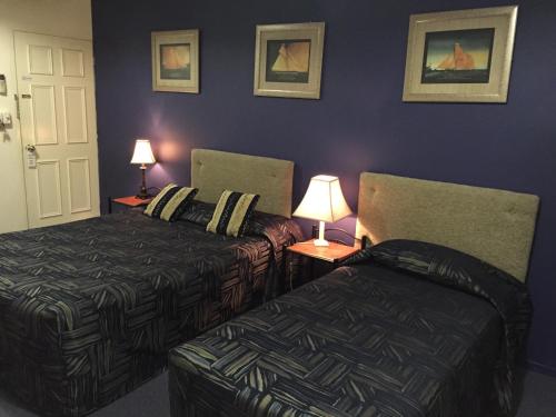 a hotel room with two beds and two lamps at Criterion Hotel-Motel Rockhampton in Rockhampton