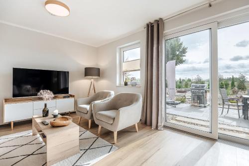 a living room with a tv and a sliding glass door at Auszeit Oase Heidi in Göhren-Lebbin